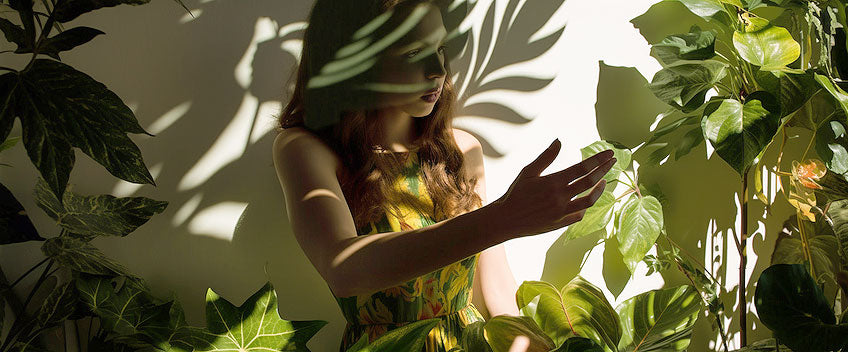 Portrait d’une femme à l’ombre de feuilles vertes.